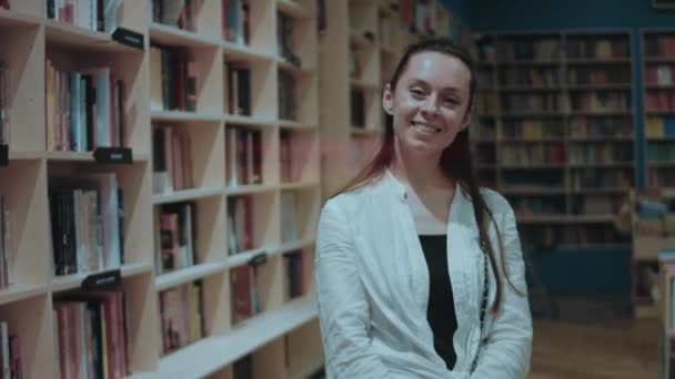 Gülümseyen Genç Kadın Boş Zamanlarını Kitapçıda Kameraya Bakarak Geçiriyor — Stok video