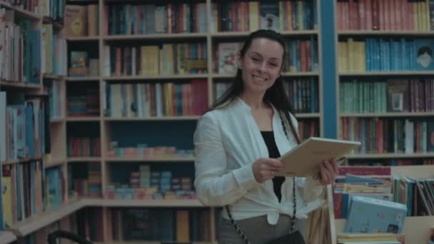 Glimlachende Jonge Vrouw Brengt Haar Vrije Tijd Door Boekhandel Kijkend — Stockvideo