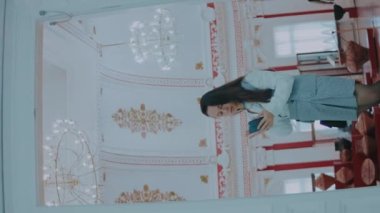 Müzedeki sergiler hakkında bilgi almak için telefon kullanan zeki genç bir kadının dikey çekimi..