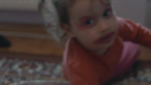 小さな白人少女が口紅とアイシャドウで顔を描きました 床に置くこと — ストック動画