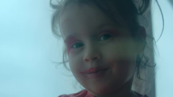 乐观而自信的高加索小孩用口红和眼药水涂了她的脸 小女孩画嘴唇和眼睑只是为了好玩 近景肖像 — 图库视频影像