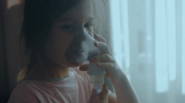 Küçük kız evde nebulizörle solunum yapıyor. Öksürük için ilaç buharlı nebulizör solumuş. Zayıflık durumu