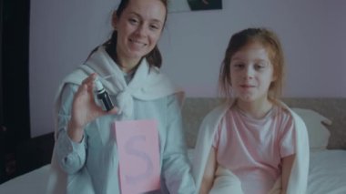 Göğsünde S harfi ve süper kahraman peleriniyle sevgili anne çocuğunun hastalığını tedavi etmek için ilaç tutuyor. Anne ve hasta kızı birlikte oturuyorlar. Süper güçleri olan bir anne. Süper anne kavramı