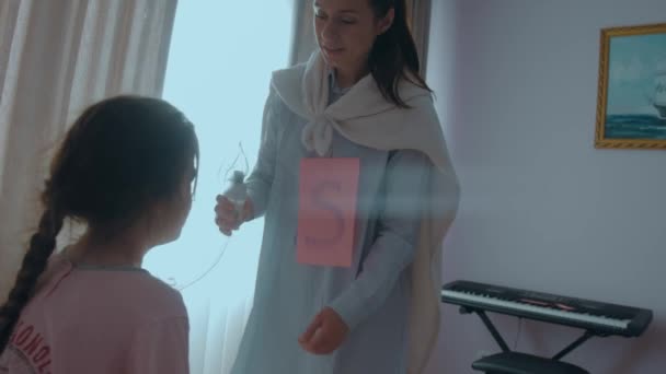 可爱的母亲胸前戴着字母S 头戴超级英雄斗篷 正在给她的孩子戴上呼吸口罩 以治疗她的病 妈妈有超能力超级妈妈的概念 — 图库视频影像