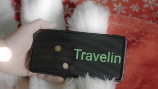 在智能手机上为圣诞题词旅行 在移动应用程序上做圣诞设计的设计师 圣诞灯和舒适的气氛 — 图库视频影像