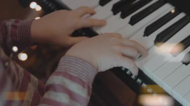 Evdeki Noel partisinde elektrikli piyano çalan küçük bir kız. Anamorfik mercek parlaması