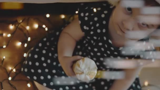 圣诞晚会上戴着圣诞老人帽的可爱小女孩在吃冰淇淋 四周都是圣诞灯 — 图库视频影像