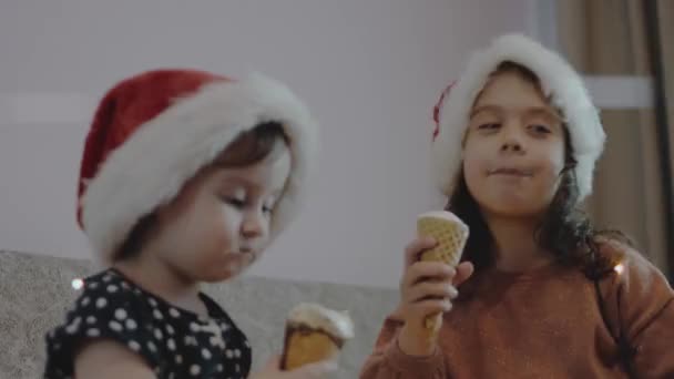 Słodkie Dziewczynki Kapeluszach Mikołajów Jedzące Lody Przyjęciu Świątecznym Światła Świąteczne — Wideo stockowe