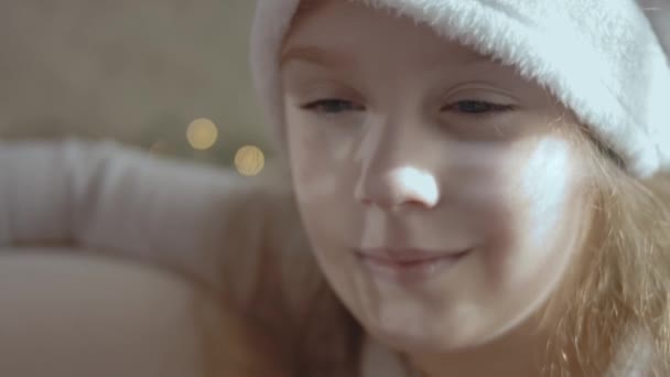 驯鹿的影子出现在戴着圣诞老人帽子的微笑的小女孩的脸上 近景肖像 — 图库视频影像