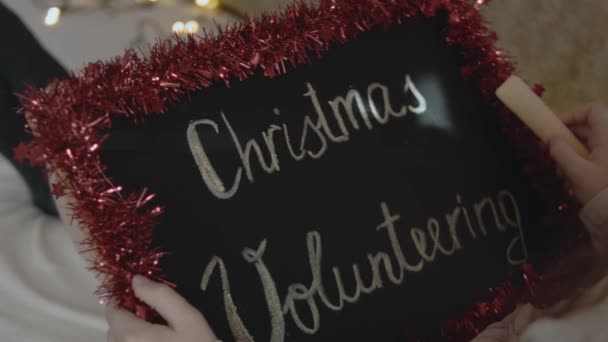 Schoolbord Met Inscriptie Kerst Vrijwilligerswerk Handen Van Een Klein Meisje — Stockvideo