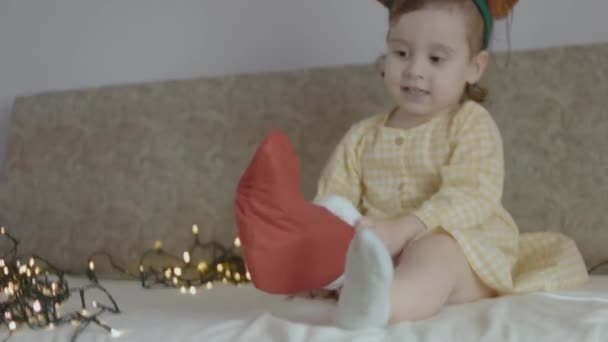 Милая Малышка Играющая Своим Рождественским Чулком Надевает Рождественский Чулок Ногу — стоковое видео