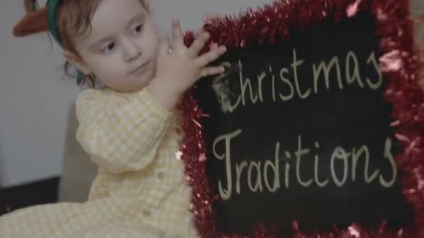 Toddler Girl Having Fun Blackboard Inscription Christmas Traditions She Erases — Stock Video