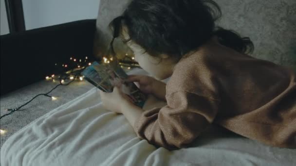 Маленька Дівчинка Дивиться Старі Фотографії Різдвяну Ніч Різдвяні Вогні Навколо — стокове відео