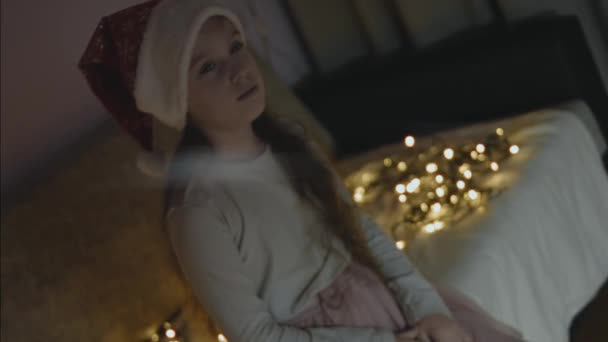 Klein Meisje Met Een Kerstmuts Die Iets Wenst Een Klein — Stockvideo