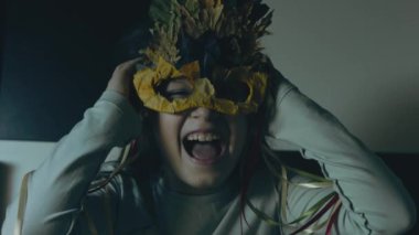 Sonbahar yaprağı maskeli küçük bir kız elleriyle kulaklarını kapatıyor, gülümsüyor ve çığlık atıyor. El bilgisayarı atışı