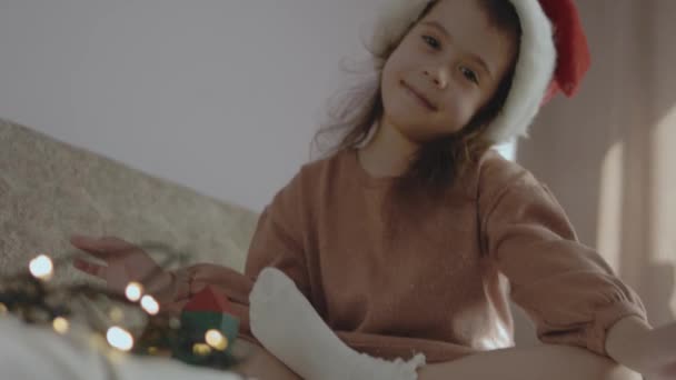 一个小女孩用彩色的建筑碎片建造了一棵圣诞树 看着相机 — 图库视频影像