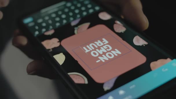 スマートフォンの非Gmoフルーツの碑文 モバイルアプリで広告デザインを行うデザイナー — ストック動画