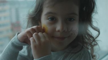 Yüzünde ayçiçeği çizimi ve tarım yazısıyla mutlu küçük bir kız. Kalp hareketini elleriyle gösteriyor. Tarım kavramı