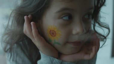 Yüzünde ayçiçeği çizimi ve tarım yazısıyla mutlu küçük bir kız. Tarım kavramı