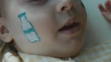 Küçük tatlı bir kızın yüzüne süt şişesi çizilmiş. Tarım konsepti. Makro, yavaş çekim.