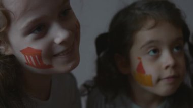 Yüzlerinde mimari temalı çizimlerle gülümseyen üç küçük kız. Mimarlık konsepti