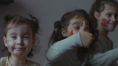 Yüzlerinde mimari temalı çizimlerle gülümseyen üç küçük kız. Süper işareti gösteriyorum. Mimarlık konsepti
