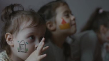 Yüzlerinde mimari temalı çizimlerle gülümseyen üç küçük kız. Mimarlık konsepti