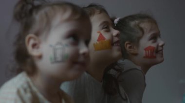 Yüzlerinde mimari temalı çizimler olan gülen üç küçük kız. Mimarlık konsepti