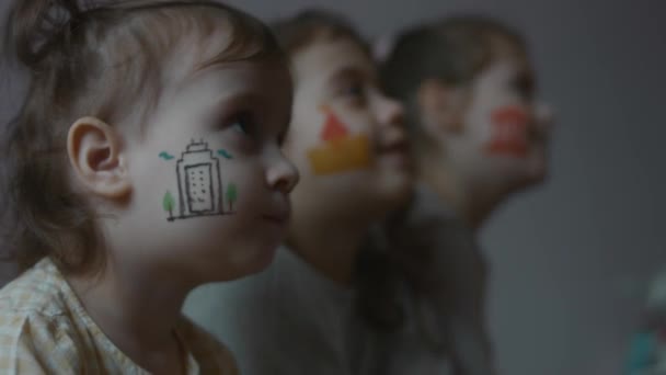 彼らの顔に建築をテーマにした絵を描いた3人の笑顔の可愛い小さな女の子 アーキテクチャコンセプト — ストック動画