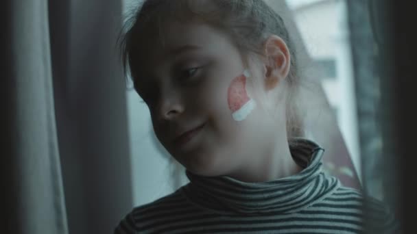 Fröhliches Kleines Mädchen Mit Weihnachtlicher Bemalung Gesicht Santas Hutmalerei Gesicht — Stockvideo