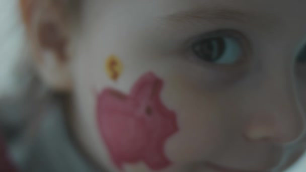 在一个可爱的蹒跚学步的小女孩的脸上画着皮吉班克的画 金融教育和存款概念 慢动作 — 图库视频影像