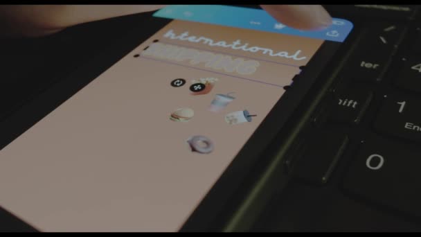 スマートフォン画面の国際配送銘柄 モバイルアプリで広告デザインを行うデザイナー 貨物および船積みの概念 — ストック動画