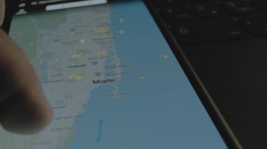 Akıllı telefon ekranında küresel haritada online uçuş takibi. Miami, Florida, ABD. Kargo, kargo ve lojistik konsepti.
