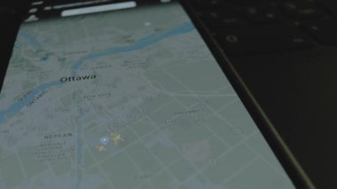 Akıllı telefon ekranında küresel haritada online uçuş takibi. Ottawa, Kanada. Kargo, kargo ve lojistik konsepti.