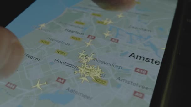 スマートフォン画面のグローバルマップ上のオンラインフライト追跡 アムステルダム オランダ 船積み 物流コンセプト — ストック動画
