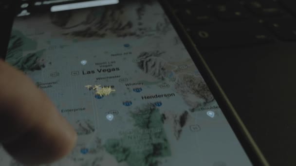 スマートフォン画面のグローバルマップ上のオンラインフライト追跡 ラスベガス アメリカ 船積み 物流コンセプト — ストック動画