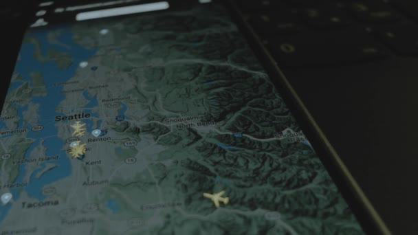 スマートフォン画面のグローバルマップ上のオンラインフライト追跡 シアトル アメリカ 船積み 物流コンセプト — ストック動画