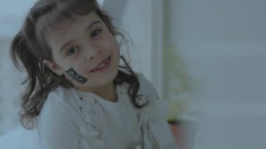 Yüzünde bilgisayar fanı resmi olan neşeli küçük bir kız. Bilgisayarlar kavramı.