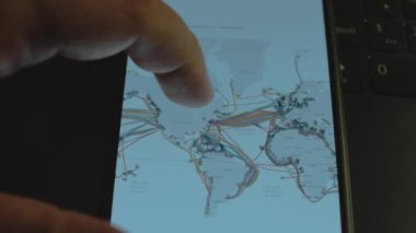 Dünya haritasındaki su altı internet kabloları akıllı telefon ekranında. Atlantik Okyanusu, Pasifik Okyanusu.