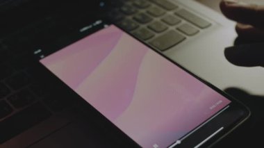 Akıllı telefon ekranındaki pembe dalgaların soyut arkaplanı. Işık ışınları ekrandan geliyor. Erkek el neşeyle kanat çırpıyor..