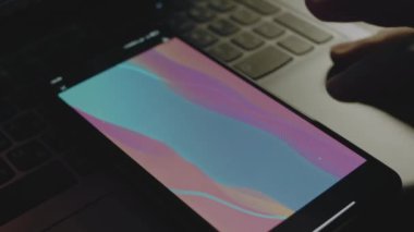 Akıllı telefon ekranındaki renkli dalgaların soyut arkaplanı. Işık ışınları ekrandan geliyor. Erkek el neşeyle kanat çırpıyor..