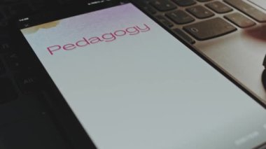 Akıllı telefon ekranında pedagoji yazıları var. Arka planda suluboya fırça darbeleriyle grafiksel sunum. Eğitim kavramı.