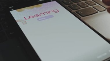 Akıllı telefon ekranından kaynak yazılarını öğreniyorum. Arka planda suluboya fırça darbeleriyle grafiksel sunum. Eğitim kavramı.