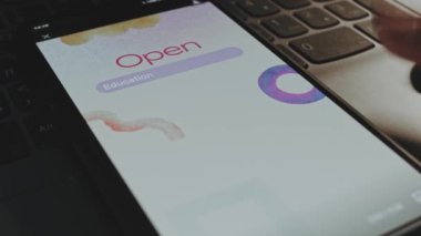 Akıllı telefon ekranında eğitim kaynakları yazısını aç. Beyaz arka planda suluboya fırça darbeleri. Erkek el neşeyle kanat çırpıyor..