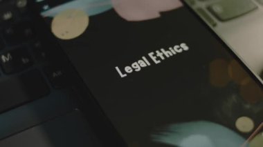 Akıllı telefon ekranında yasal etik yazıları var. Bokeh ışıklarıyla siyah arkaplan üzerine grafiksel sunum. Işık ışınları. Hukuki kavram.