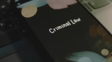 Akıllı telefon ekranında ceza hukuku yazıları var. Bokeh ışıklarıyla siyah arkaplan üzerine grafiksel sunum. Işık ışınları. Hukuki kavram.