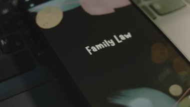 Akıllı telefon ekranında aile hukuku yazıları var. Bokeh ışıkları titreşen siyah arkaplan üzerine grafiksel sunum. Işık ışınları. Hukuki kavram.