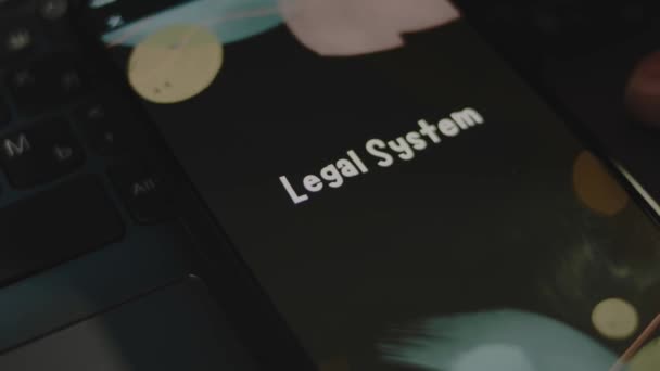 スマートフォン画面の法的なシステムの碑文 ブラックバックグラウンドのグラフィックプレゼンテーションとボケーライト ライトレイ 法律コンセプト — ストック動画