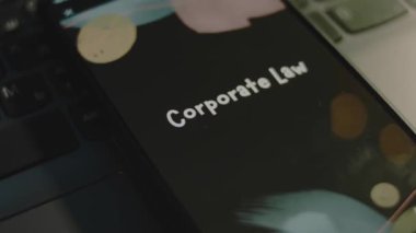 Akıllı telefon ekranında kurumsal hukuk yazıları var. Bokeh ışıkları titreşen siyah arkaplan üzerine grafiksel sunum. Işık ışınları. Hukuki kavram.