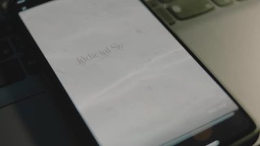 Akıllı telefon ekranında Yargı Sistemi yazıları. Huzurlu su ve deniz kumu dalgalarını gösteren grafiksel bir sunum. Hukuki kavram.